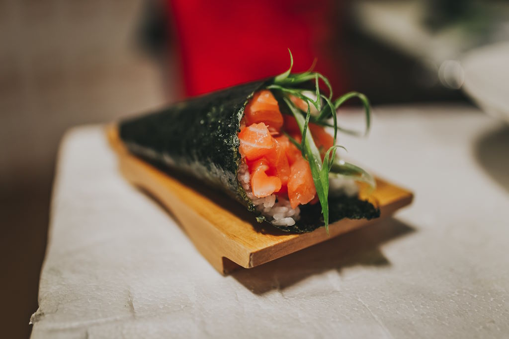 Sushi en forma de cono, hecho con una hoja de nori rellena de arroz, pescado y vegetales, que se come con la mano. Es una forma divertida y casual de disfrutar del sushi, permitiendo una amplia variedad de rellenos y personalización. En España, el temaki se presenta como una opción innovadora y social para disfrutar del sushi, ideal para reuniones informales donde cada comensal puede crear su propio rollo según sus preferencias, fusionando la tradición japonesa con la creatividad individual.