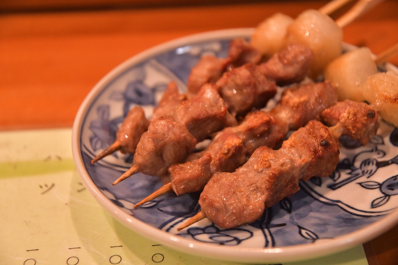 El yakitori, brochetas de pollo asadas sobre carbón, es un plato que captura la esencia de la cocina japonesa con su simplicidad y profundidad de sabor. Cada parte del pollo, desde el pecho hasta la piel, se utiliza en el yakitori, demostrando un profundo respeto por los ingredientes y la minimización del desperdicio. Las brochetas se sazonan típicamente con sal o una salsa a base de soja, conocida como tare, antes de ser asadas a la perfección. Esta combinación de sazón y técnica de cocción produce un plato humilde pero profundamente satisfactorio, muy apreciado en bares y restaurantes españoles.