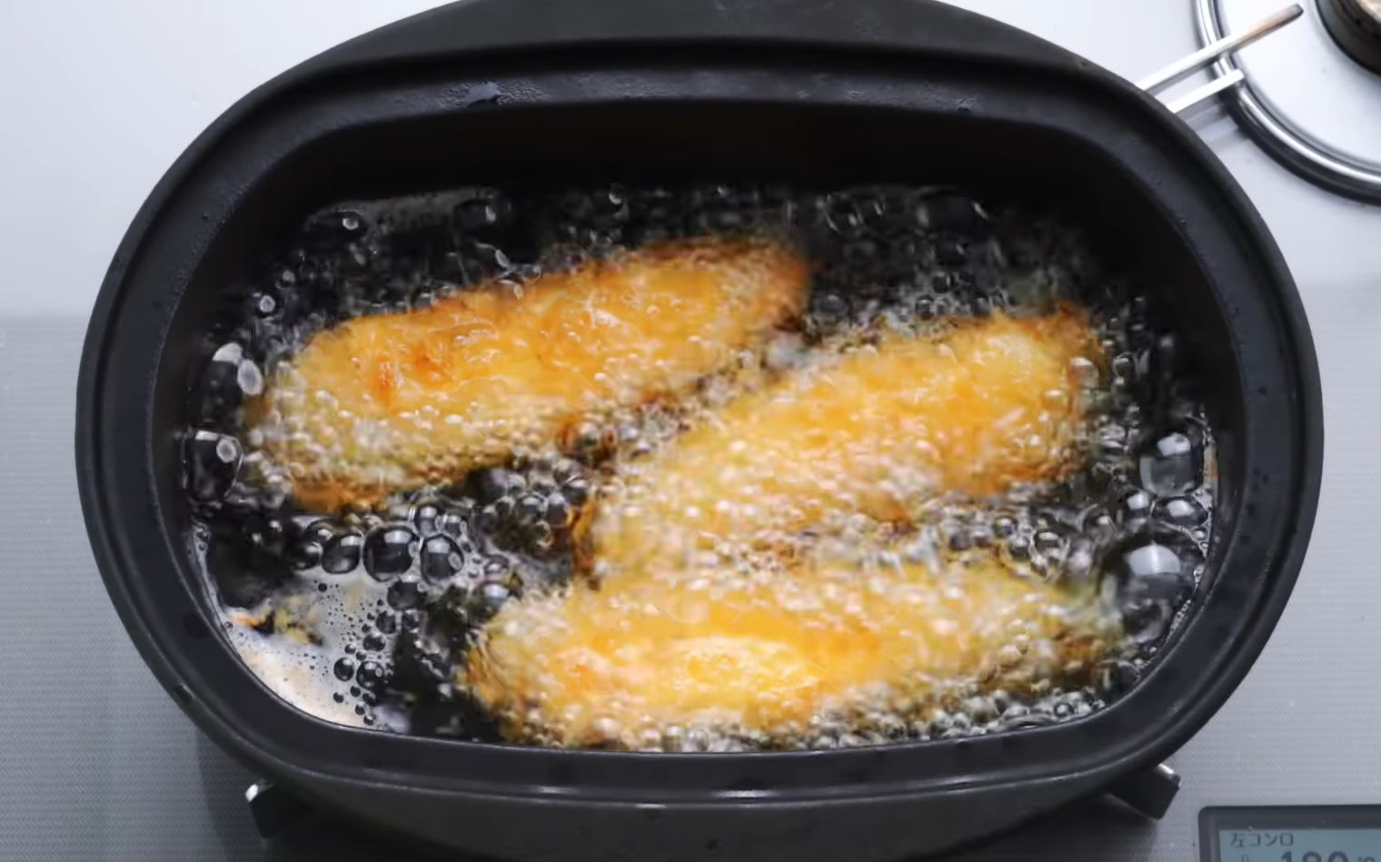 Tiras de pechuga de pollo rebozadas con panko friéndose a 180 grados