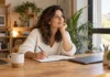 Copywriting: aprende a escribir textos que ayudan a vender Mujer preparando un texto en un cuaderno junto a un portátil cerrado.