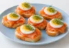 Pintxo de salmón y huevo Rebanadas de pan con salmón ahumado, rodajas de huevo duro y puntas de eneldo.