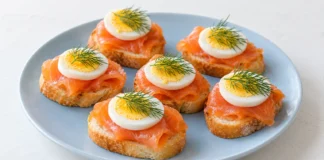 Pintxo de salmón y huevo Rebanadas de pan con salmón ahumado, rodajas de huevo duro y puntas de eneldo.