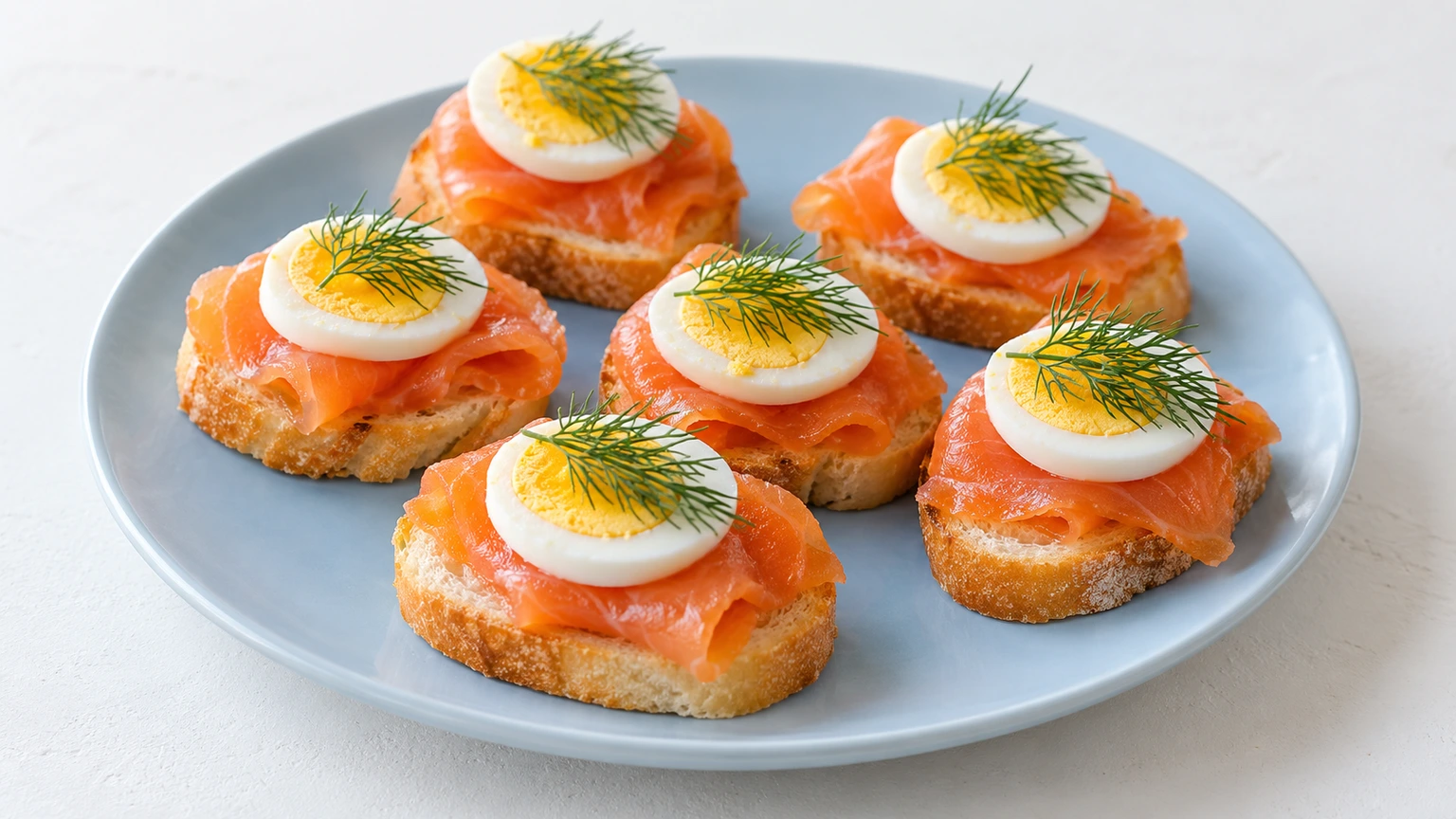 Rebanadas de pan con salmón ahumado, rodajas de huevo duro y puntas de eneldo.
