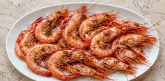 Gambas a la plancha Gambas enteras a la plancha con cristales de sal sobre una fuente blanca.
