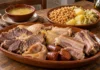 Cocido maragato Fuente de carnes de cocido maragato con garbanzos, repollo y patatas en segundo plano junto a la sopa.