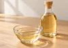 Mirin: qué es y cómo utilizarlo en la cocina japonesa Mirin dorado y transparente en un cuenco de cristal junto a una botella sin etiqueta.