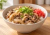 Receta de gyudon: arroz con ternera y cebolla Cuenco de gyudon con arroz blanco, ternera en lonchas finas, cebolla, cebolleta y jengibre encurtido rojo.